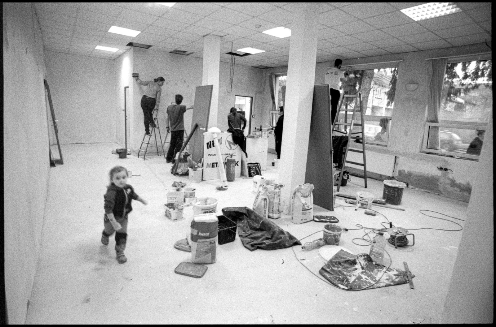 Černobílá fotografie dobrovolníků a dětí při přípravě prostoru