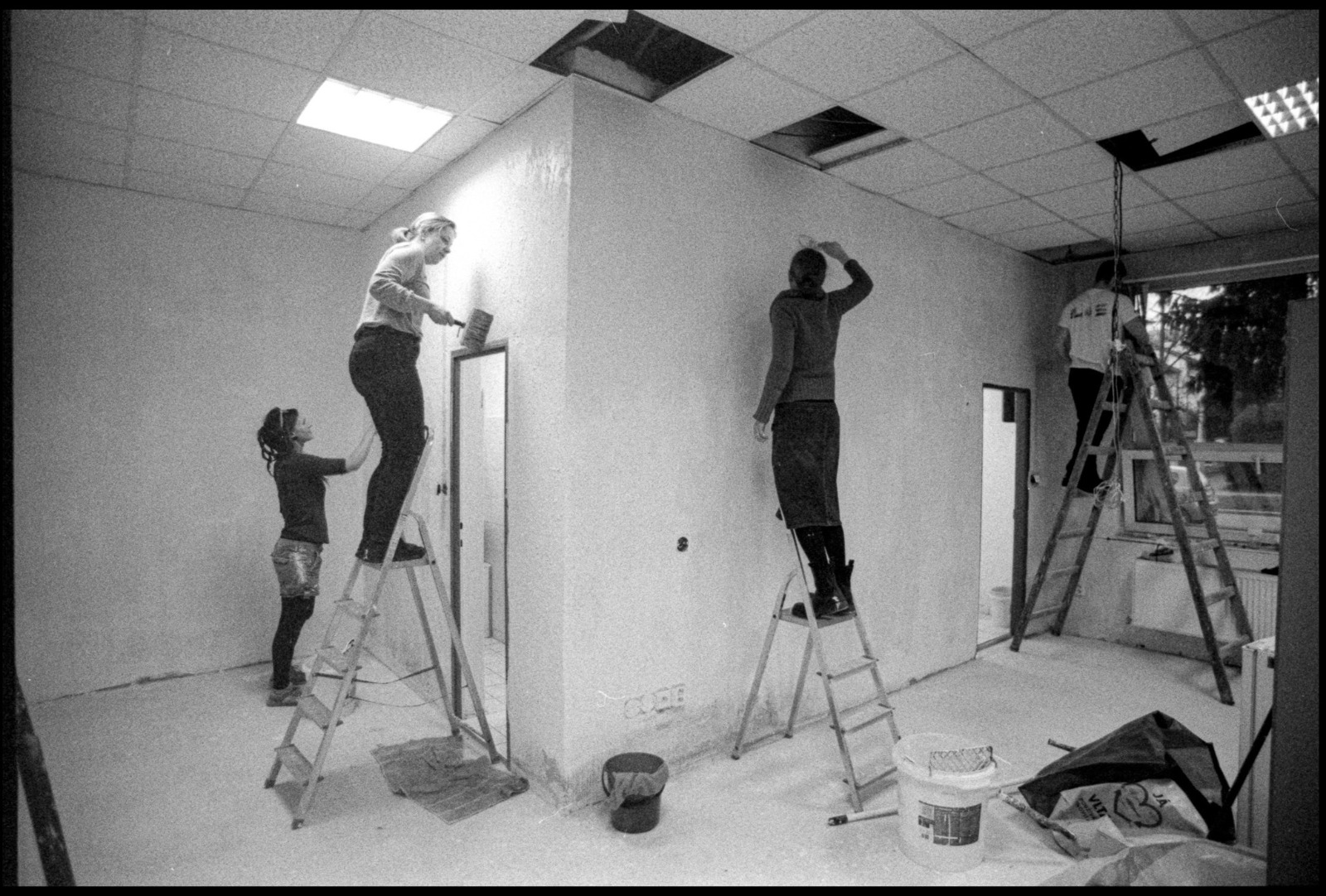 Černobílá fotografie dobrovolníků při malování stěn
